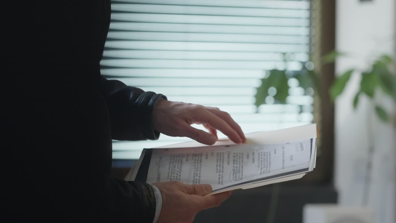 Suited man quietly reviews documents inside a secret folder. The scene suggests discretion, classified information, or covert activity— Espionage, corporate intrigue, or internal investigations. spy