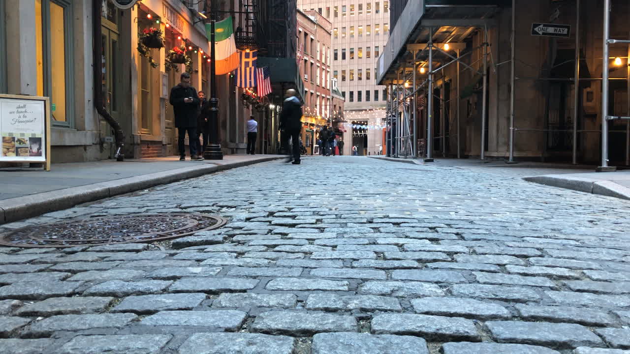 Bar lined cobblestone street in downtown manhattan.Motion Time Lapse pan left to right low angle bar goers walking.