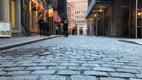 bar lined cobblestone street in downtown manhattan.motion time lapse pan left to right low angle bar goers walking.
