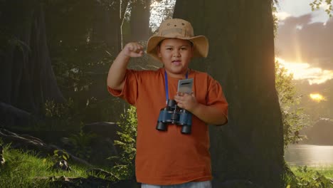niño asiático con sombrero y binoculares mirando su teléfono inteligente y luego gritando meta celebrando mientras explora la naturaleza del bosque. niño investigador examina algo, concepto de aventura de turismo de viaje