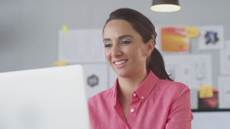 Businesswoman-In-Office-Making-Video-Call-At-Desk-On-Laptop