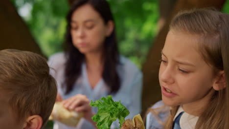 relaxed girl eat sandwich on picnic close up. mother feeding labrador on nature.