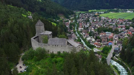 landscape of a castle in a village, wooded valley between mountains and a river