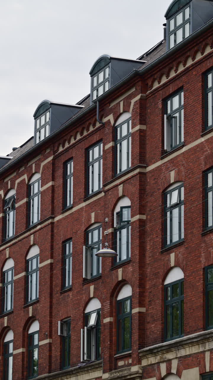 Edificio tradizionale in mattoni con una guglia classica ed eleganti abbaini sotto un cielo nuvoloso. Copenaghen, Danimarca