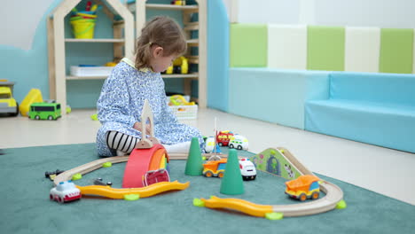 little girl playing toy cars racing on floor at home