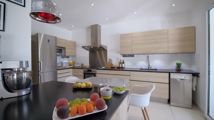 Ripresa panoramica di una cucina moderna con frutta fresca sul tavolo, primo piano.