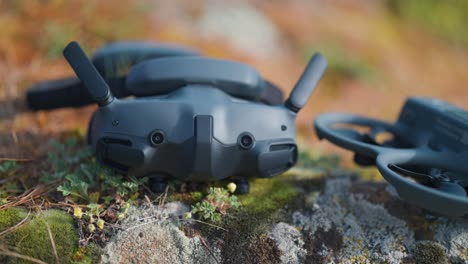 FPV-drone-goggles-near-aircraft-on-outdoor-surface-with-rock-and-grass