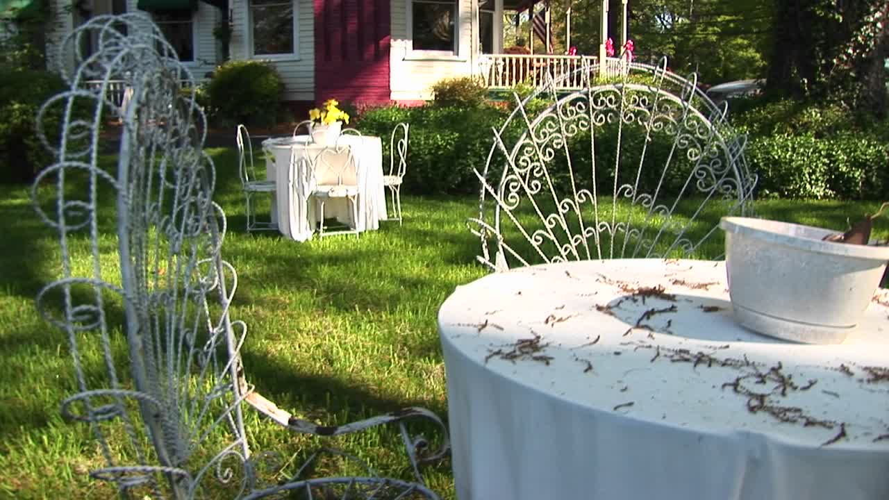 테이블과 의자는 밝은 빨간색 굴뚝 옆에 있는 빅토리아풍 주택의 마당을 제공합니다.