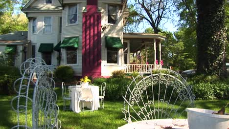 Tables-And-Chairs-Furnish-The-Yard-Of-A-Victorian-Home-Flanked-By-A-Bright-Red-Chimney