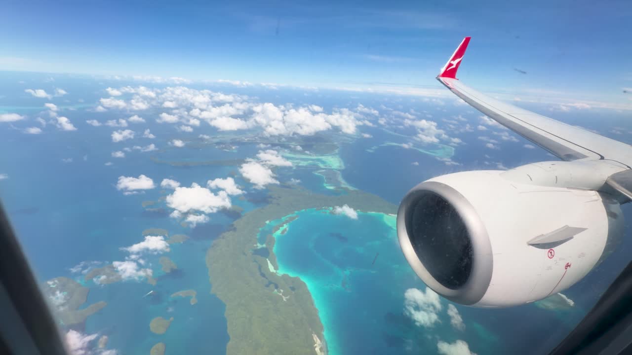 Vinduesudsigt fra fly fanger en jetmotor, der flyver over turkise laguner og tropiske Palau-øer.