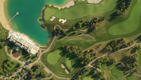 aerial overhead view of a golf resort with beautiful abstract patterns, sand traps, trees tennis courts, and a turquoise lake