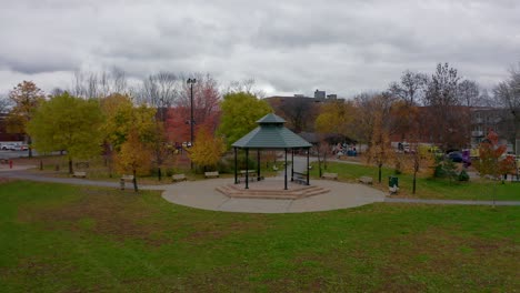 drone slowly flying around a gazebo in a public park on a fall morning