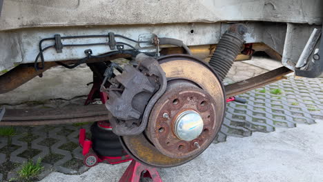 Close-up view of a car&#039;s suspension and brake system being repaired, with tools in the foreground