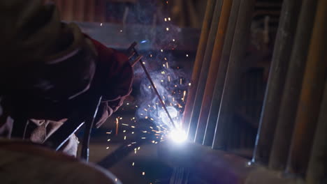 Welder-connects-thin-steel-pipes-to-larger-tube-in-workshop