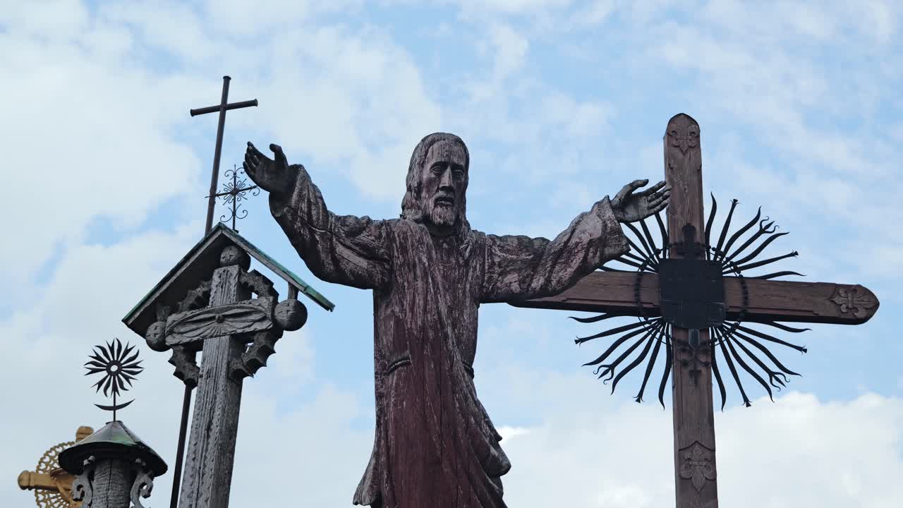 Slow zoom reveals detailed wooden statue and crosses at Hill of Crosses site