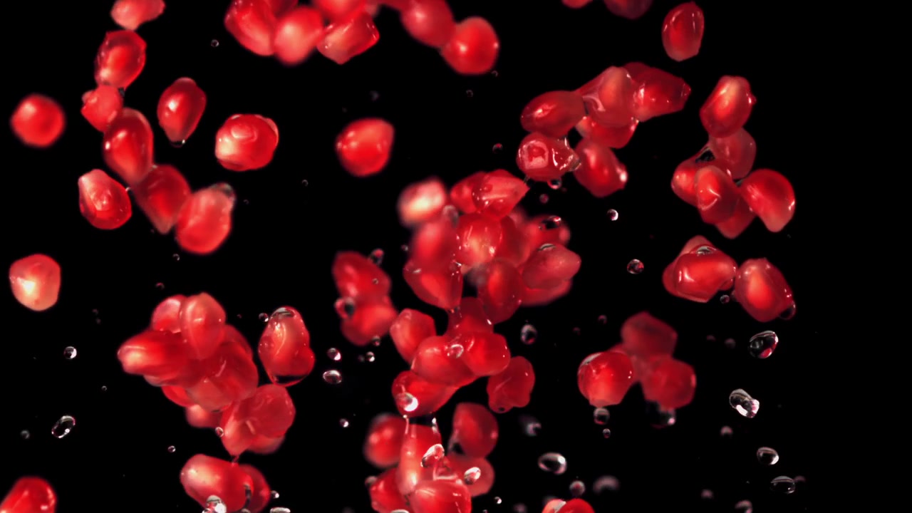 Vibrant Red Pomegranate Seeds and Water Droplets Falling on Black Background