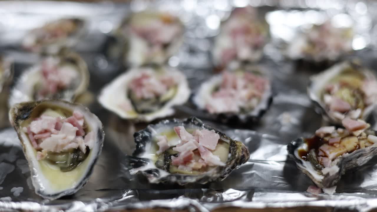 Oysters being prepared with toppings on baking tray