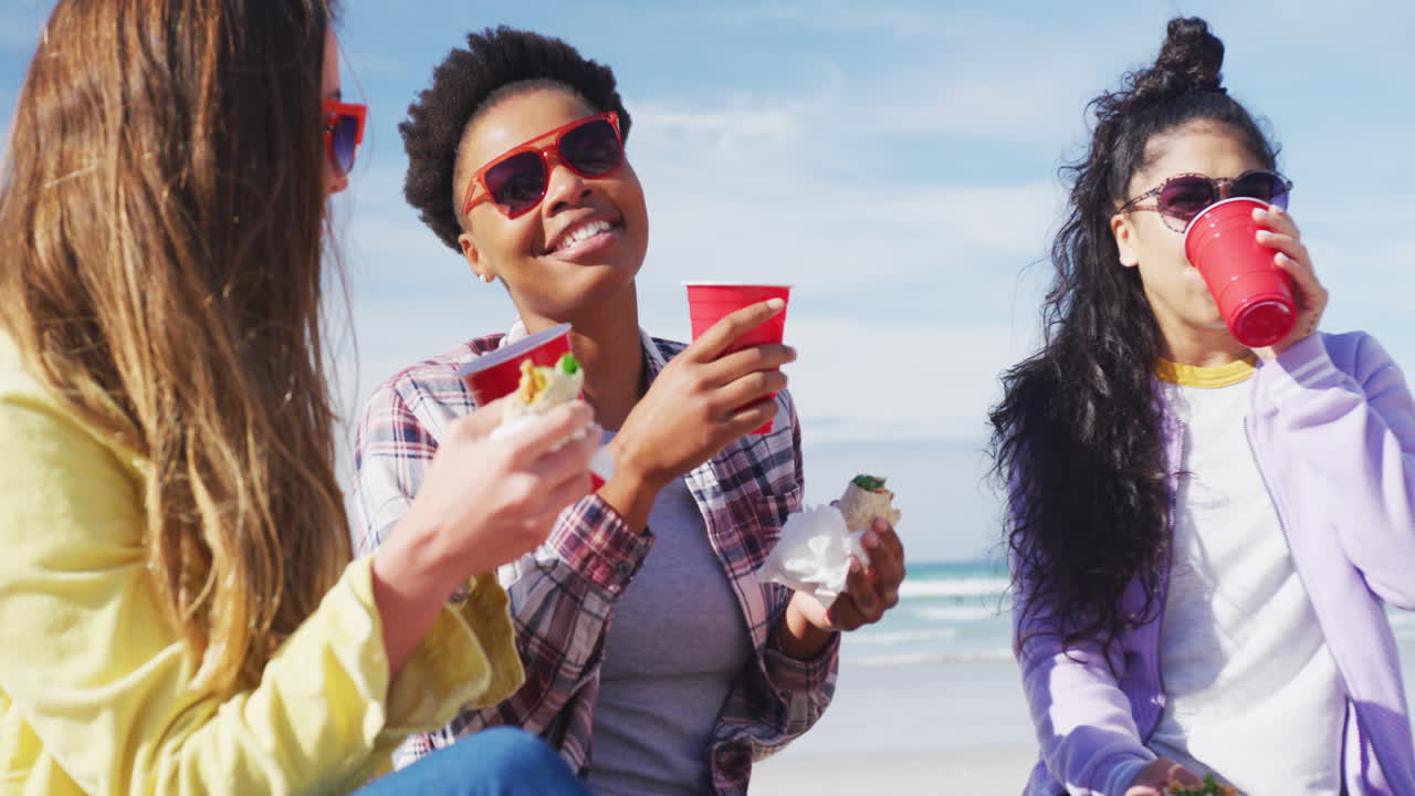 un grupo feliz de amigas diversas divirtiéndose, haciendo picnic en la playa