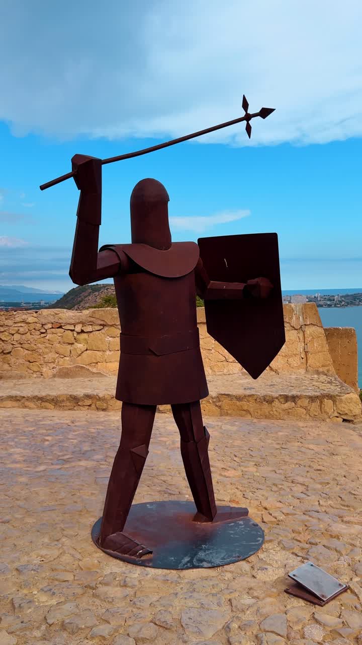 Riddarstaty i metall vid Santa Barbara-slottets utsiktsplats. Silhuett av en rostig metallskulptur föreställande en riddare med spjut och sköld, mot havet.
