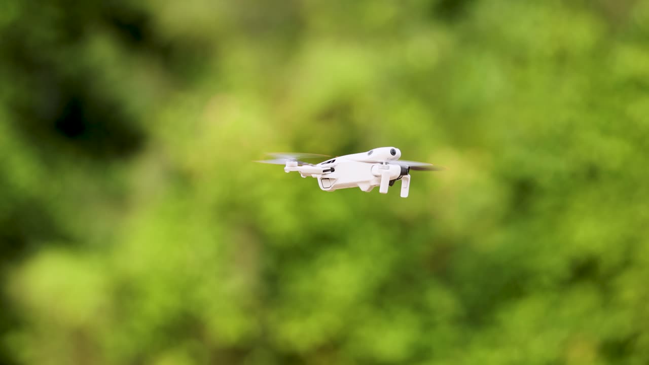 A drone hovers steadily against a vibrant green backdrop, captured with smooth camera movement and natural lighting