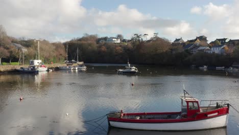 an ascending aerial shot revealing boats anchored in the river brandon on a quiet fall morning in kinsale, ireland