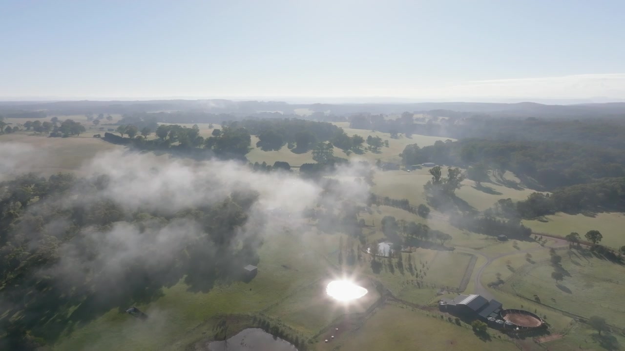 Dronebilde av lav morgentåke som driver over jordbruksland og landlige eiendommer i Southern Highlands, New South Wales, Australia