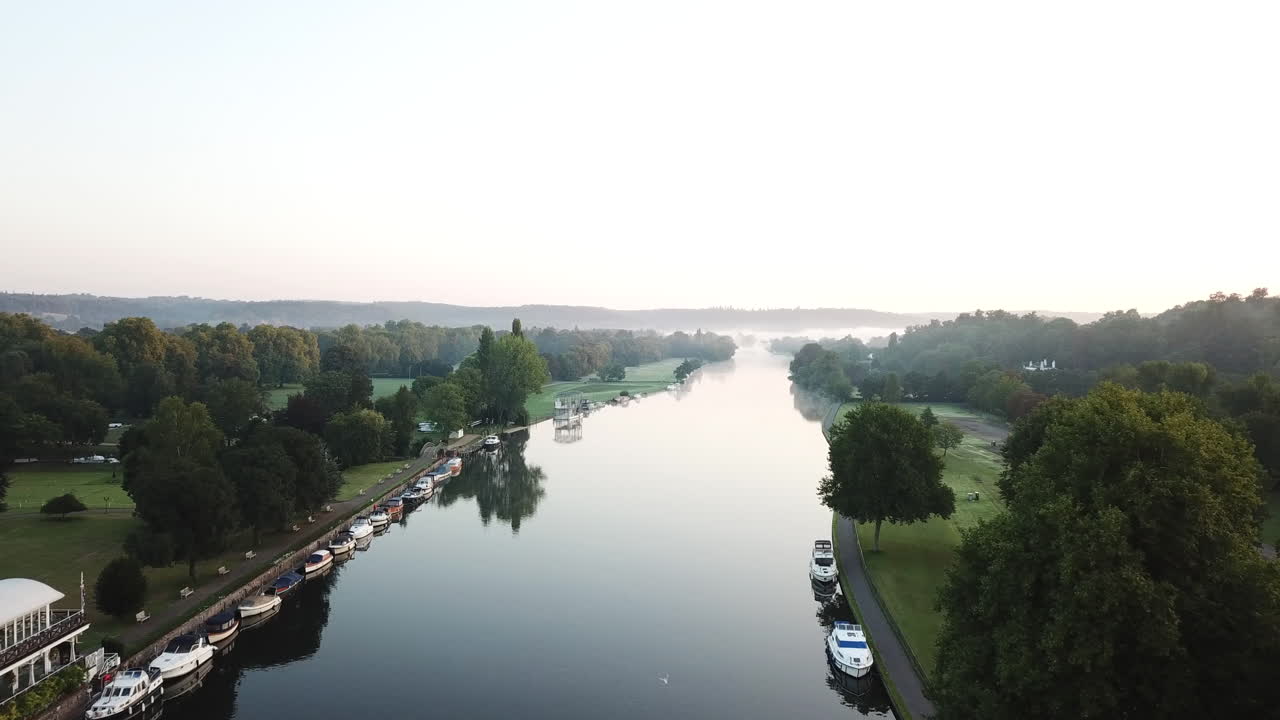 Splendida ripresa drone di Henley-on-Thames all'alba, sorvolando il fiume verso est con una leggera nebbia sul fiume e sulle colline e i campi circostanti.