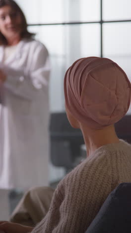 vertical video of young woman patient wearing headscarf being called for chemotherapy treatment for breast cancer in hospital clinic