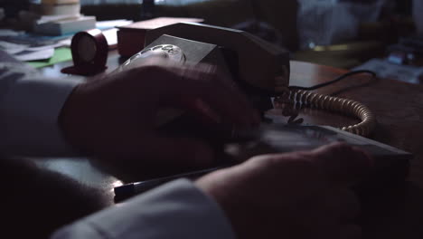 Una-Persona-Con-Una-Camisa-Blanca-En-Un-Escritorio,-Comiendo-Un-Número-En-Un-Organismo-Telefónico,-Marcando-Y-Hablando-Por-Un-Viejo-Teléfono-De-Disco-Y-Tomando-Notas