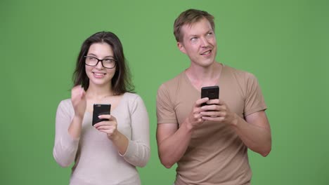 young happy couple using phone and thinking together
