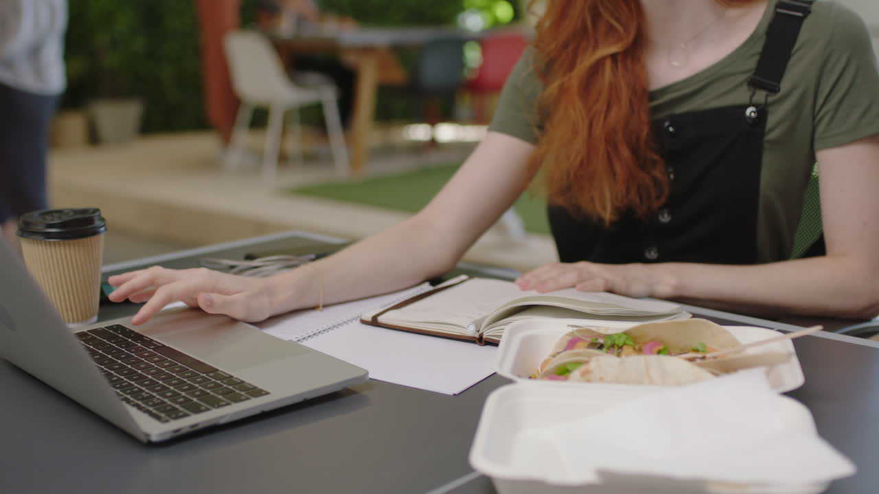 joven mujer de negocios caucásica escribiendo notas disfrutando del estudio escuchando música usando auriculares estudiante trabajando en una oficina multiétnica ocupada