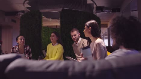 muslim woman in a modern open space coworking office giving a presentation to team. middle eastern arab businesswoman in creative startup office. disabled businessman in a wheelchair on team meeting