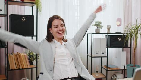 Businesswoman-freelancer-taking-break-leaning-on-chair-after-working-celebrating-success-victory-win