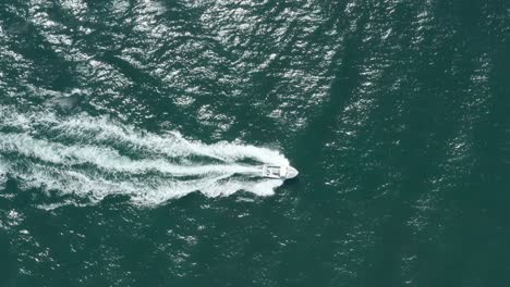 Von-Oben-Nach-Unten-Folgen-Sie-Der-Drohnenaufnahme-Eines-Kleinen-Schnellboots-In-Einem-Blauen-Meer