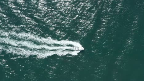 top down follow drone shot of small speed boat in a blue sea