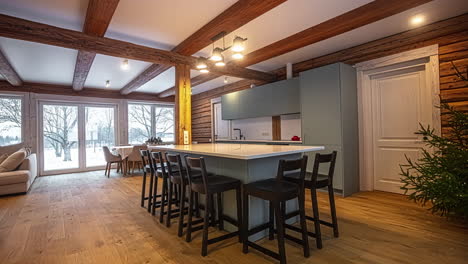 Panning-view-of-living-room-and-kitchen-of-modern-and-elegant-house-and-snowy-landscape-outside-windows