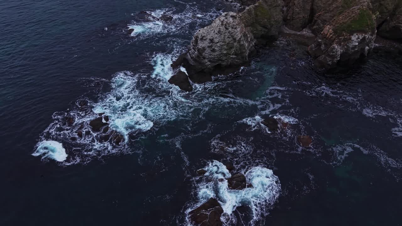 Le onde si infrangono sulle rocce in una zona costiera nelle prime ore della sera