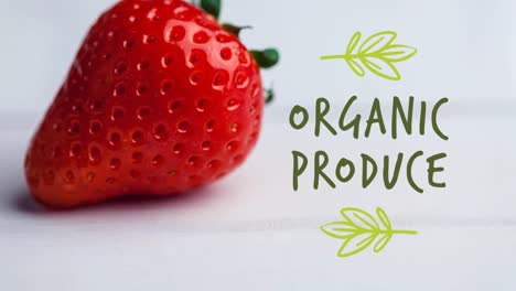 Animation-of-organic-produce-text-in-green-over-fresh-organic-strawberry