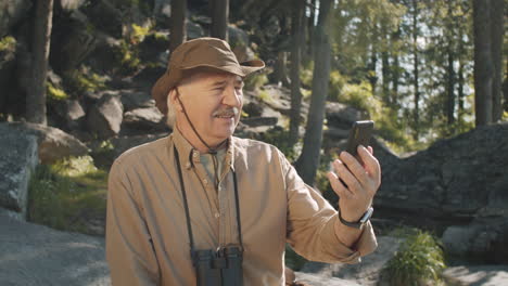 hombre mayor tomando una llamada de video selfie en un bosque