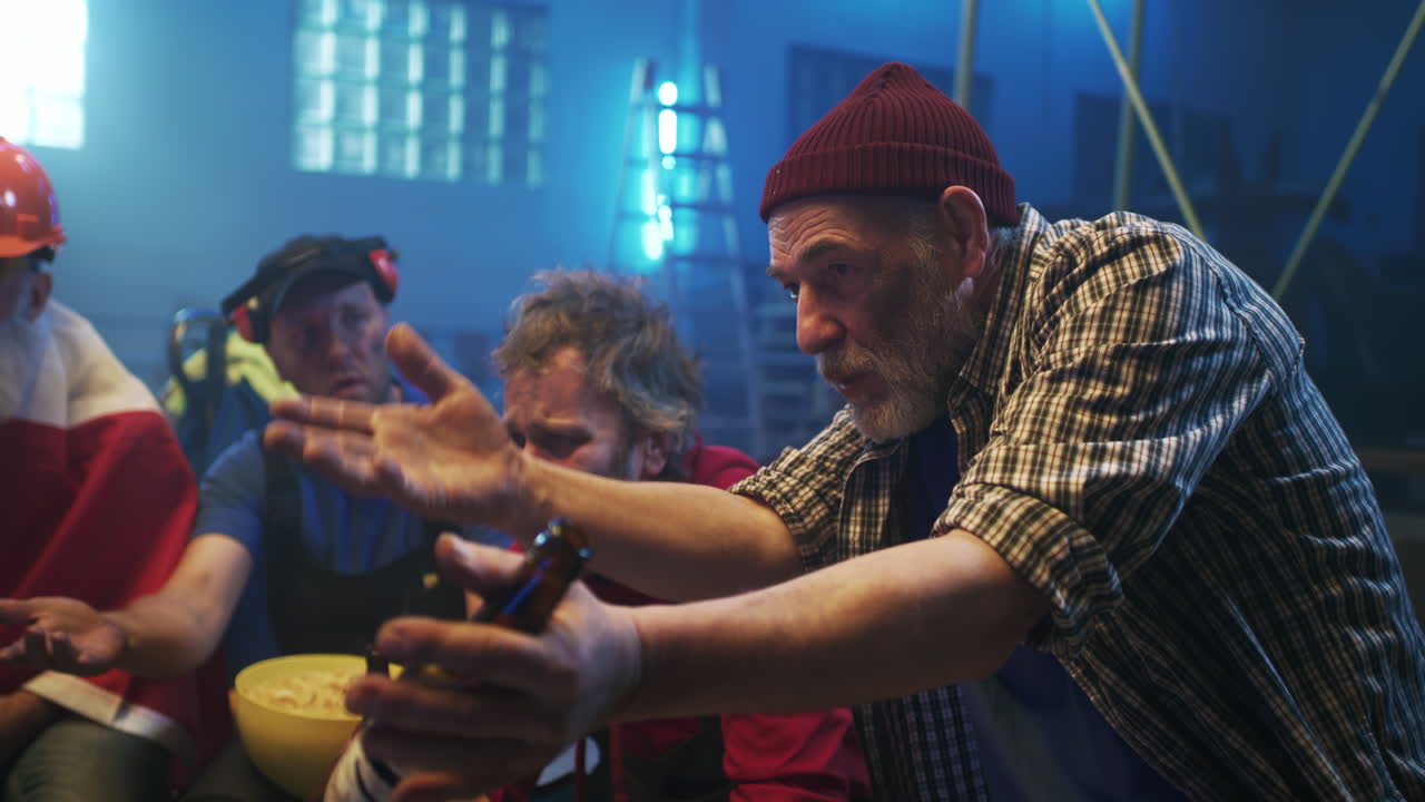 A group of men having a casual gathering, sharing snacks and beer in a workshop, engaged in an animated conversation