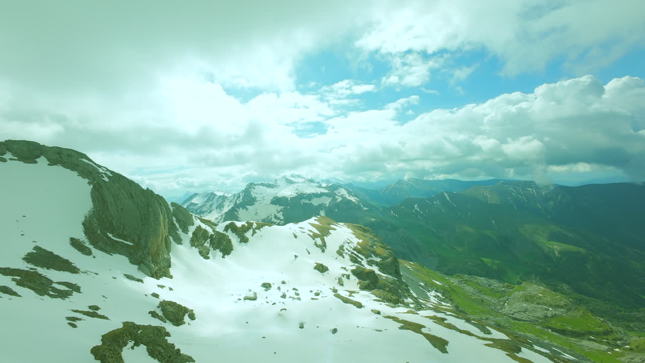 Drone view of the top of a mountains with snow and clouds