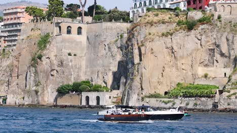 boat travels along cliffside in sorrento, naples