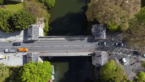 top down of flowing traffic moving from left to right over a traditional old european or english road bridge