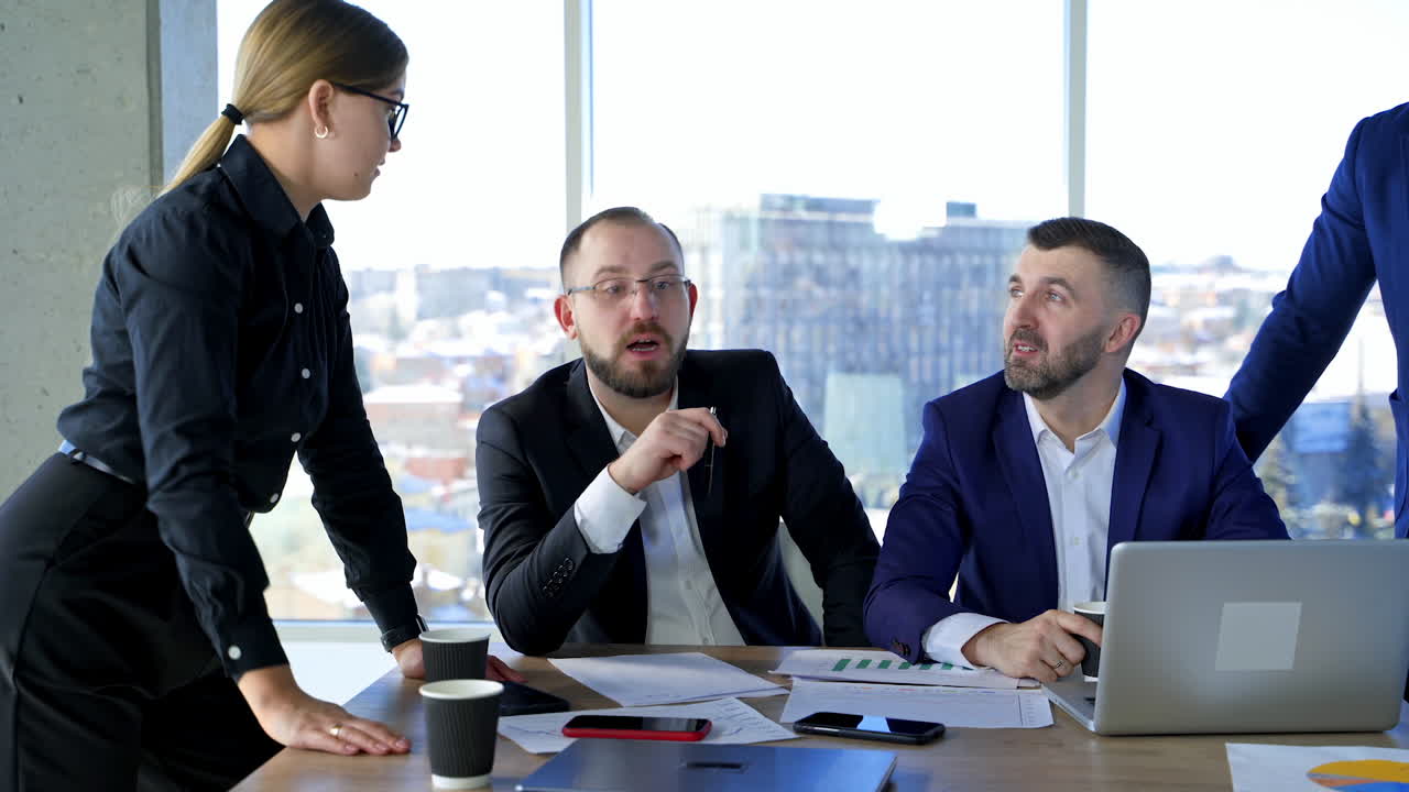 Happy business partners work in office center. Group of entrepreneurs having a conversation on window background with city view.