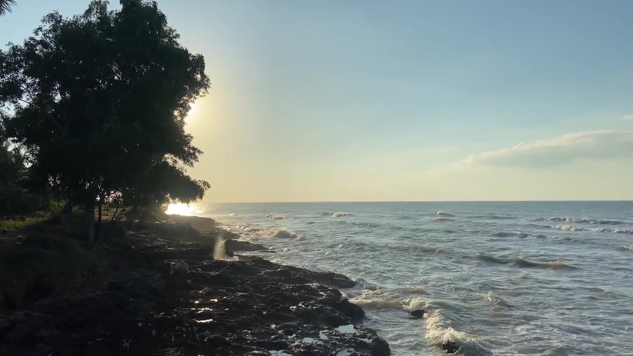 Le serene onde dell'oceano si schiantano sulla costa rocciosa al tramonto