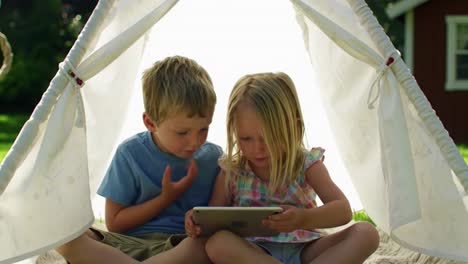 children happily watching content on tablet inside play tent