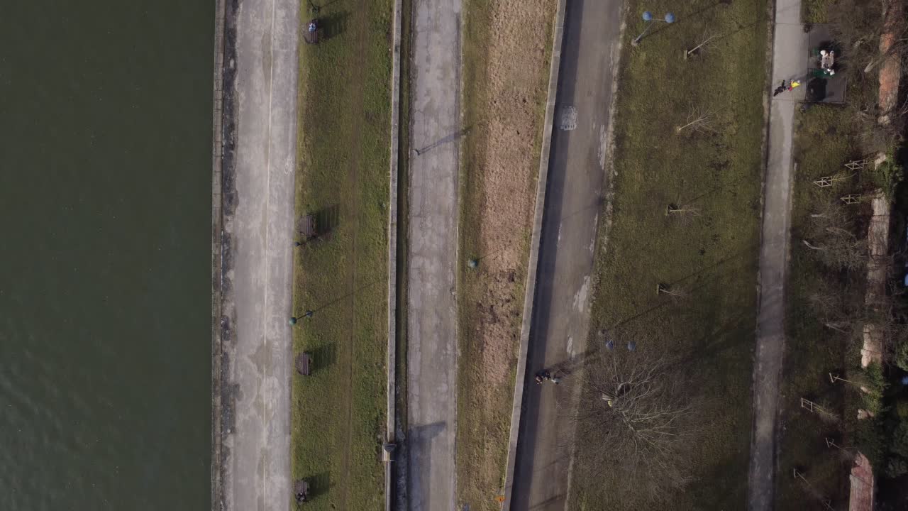 Luftfoto set direkte ned af en park ved floden med gående mennesker