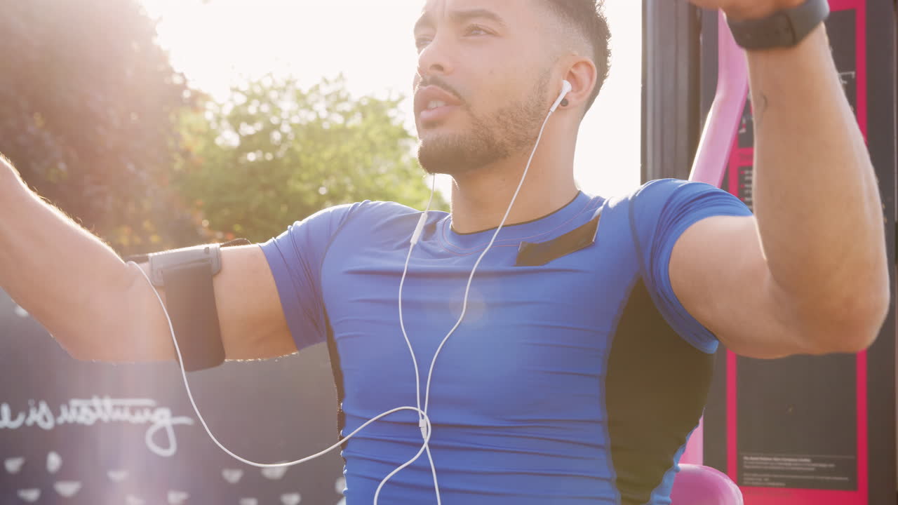 joven atleta masculino usando gimnasio al aire libre, retroiluminado