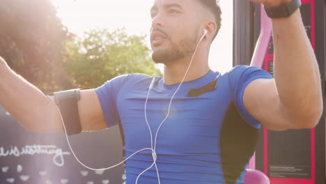 Young-male-athlete-using-outdoor-gym,-backlit