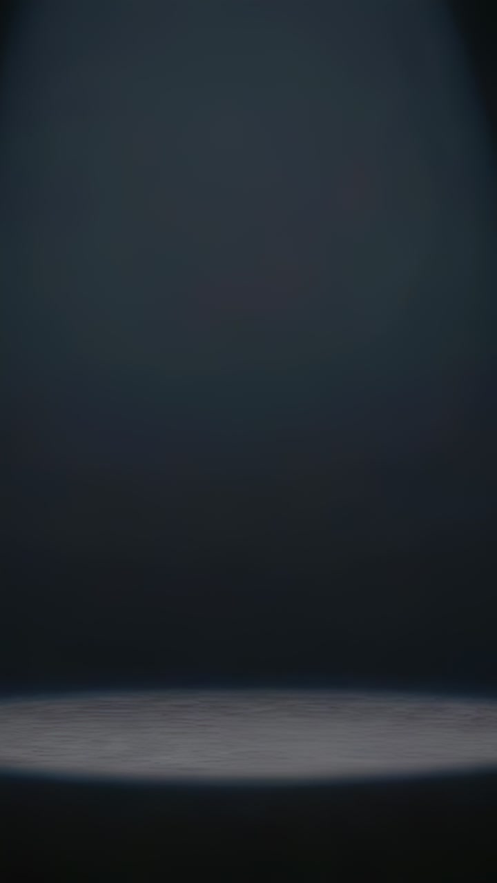 Vertical video: Appearing diffuse pool of light on stage floor with dark backdrop, creating mood